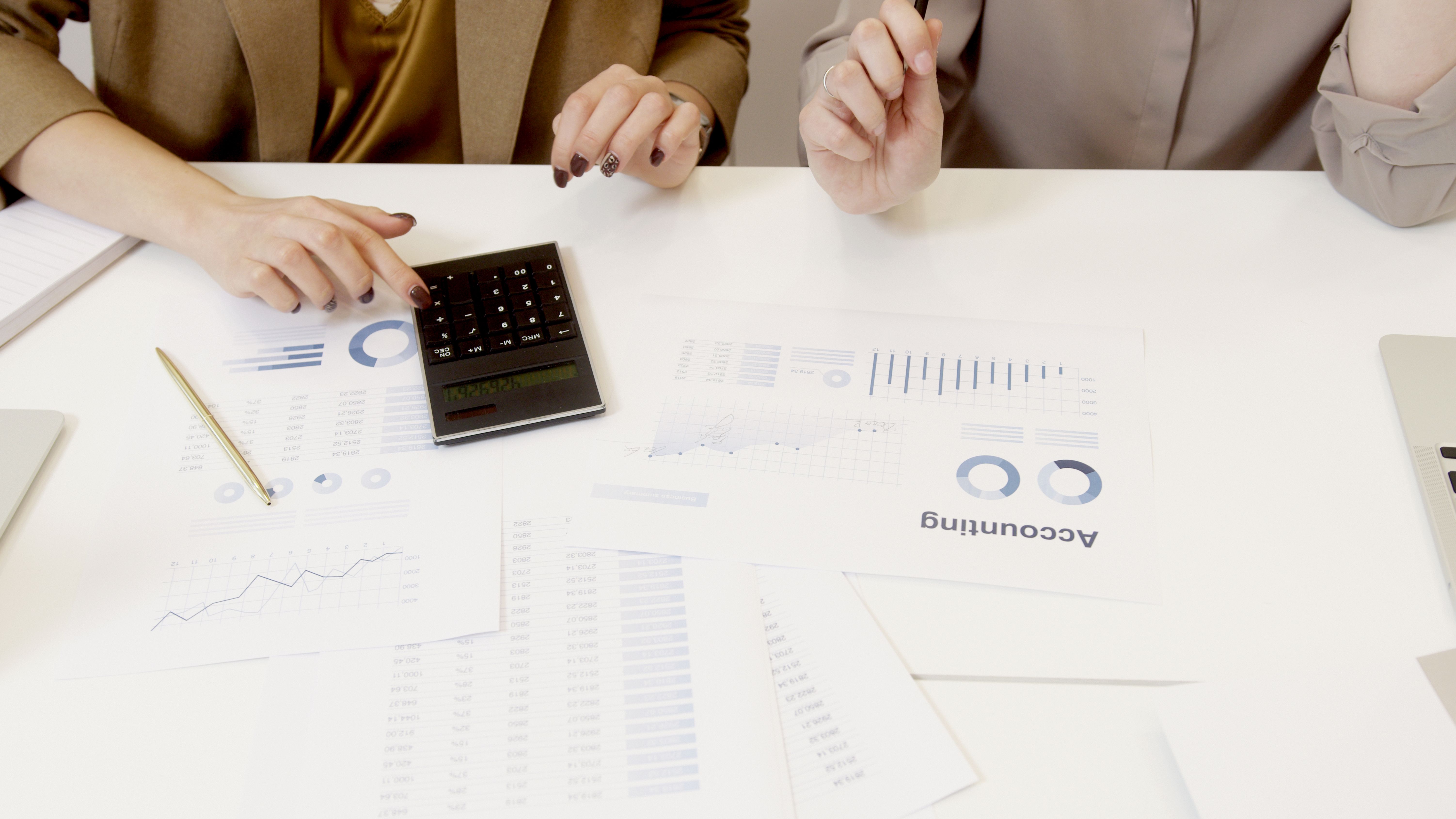 Two professionals analyzing financial documents with a calculator